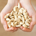 Ripe cashew nuts in woman's hands forming heart shape